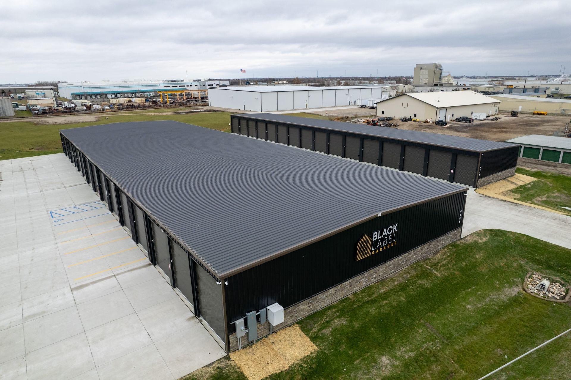 Aerial view of large industrial warehouse buildings with a parking lot and grassy areas.