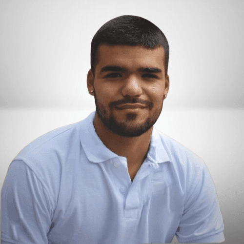 Man in a white polo shirt smiling with a neutral background.